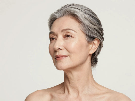 Mujer madura de cabello plateado con piel luminosa y saludable, cuidado facial en la menopausia